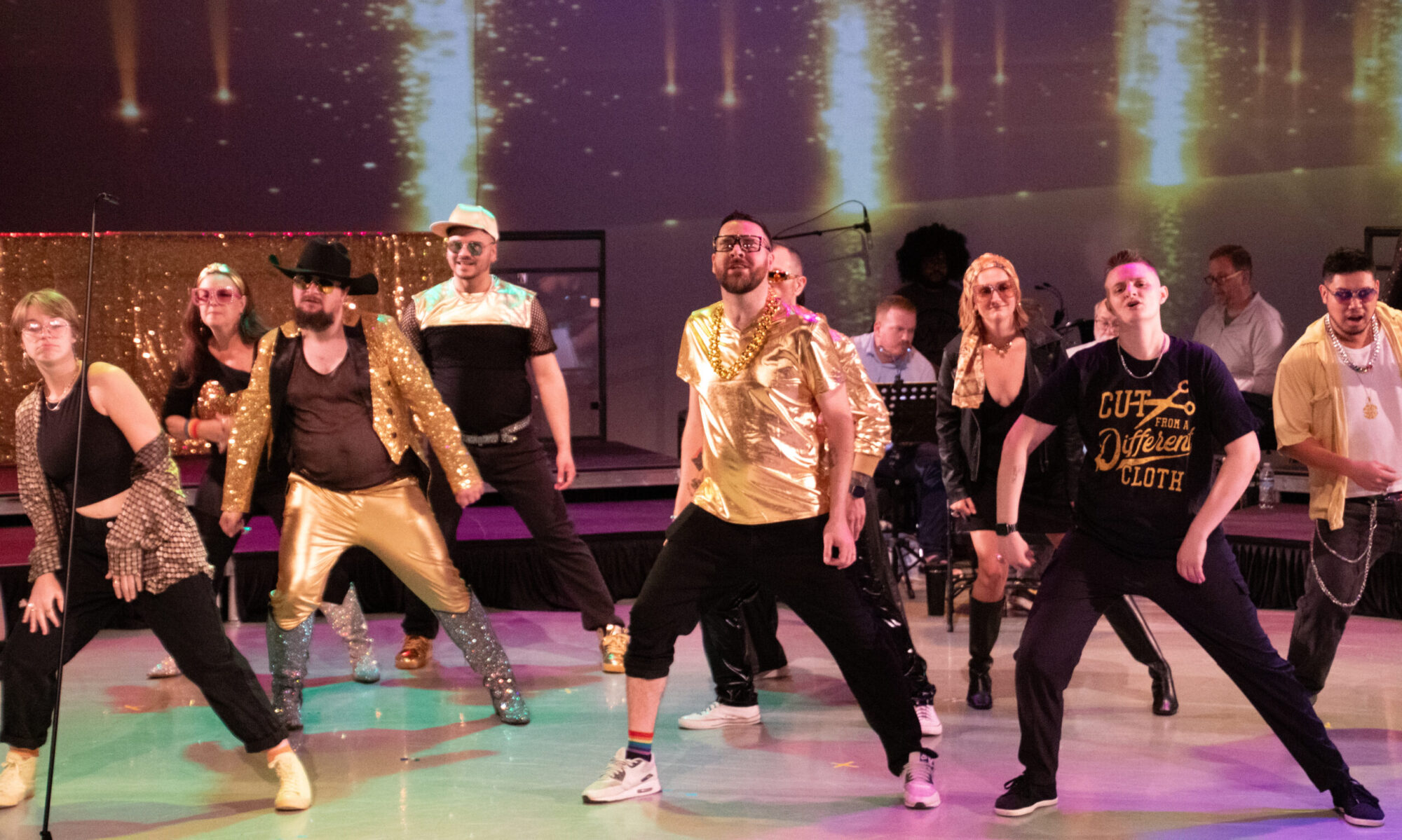 Singers dressed in black and gold do a dance during a performance